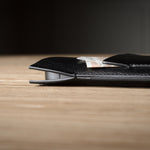 Close-up of a black leather iphone case on a wooden surface with a dark background