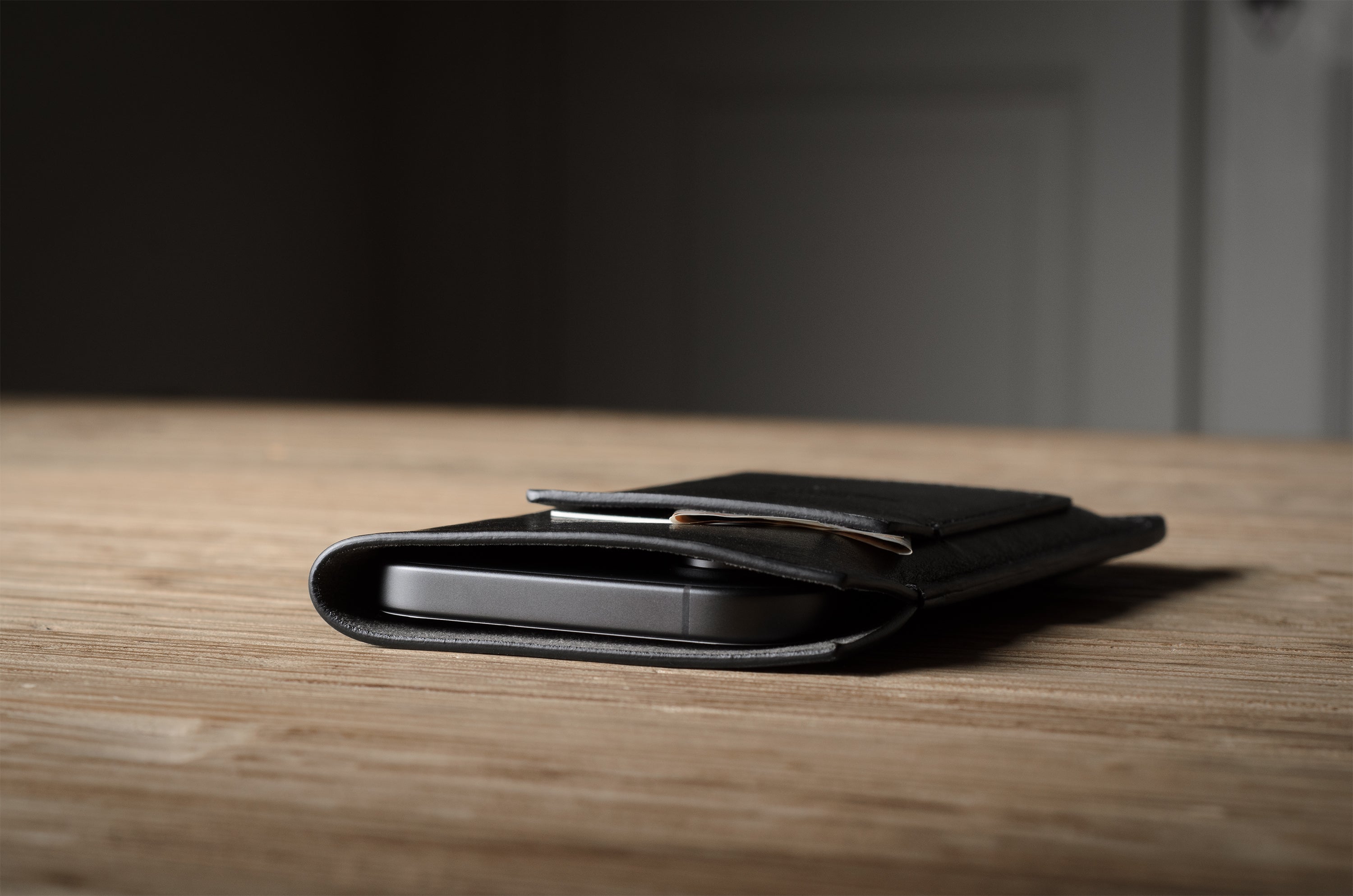 Black iphone case on a wooden surface with a blurred background