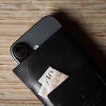 Black iphone case with a card sticking out on a wooden surface