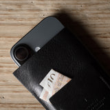 Black iphone case with a card sticking out on a wooden surface