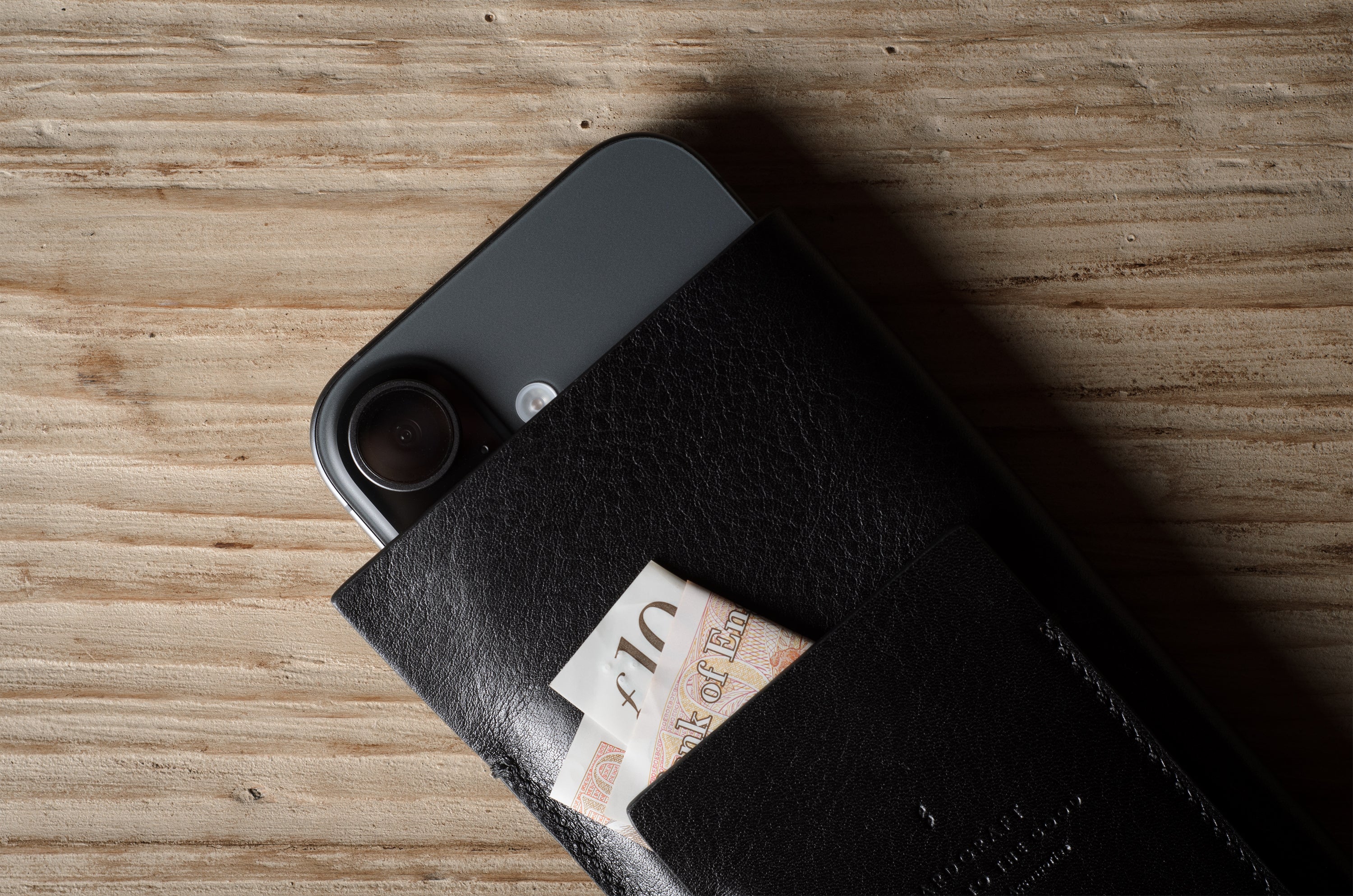 Black iphone case with a card sticking out on a wooden surface