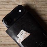 Black iphone case with a card on a wooden surface