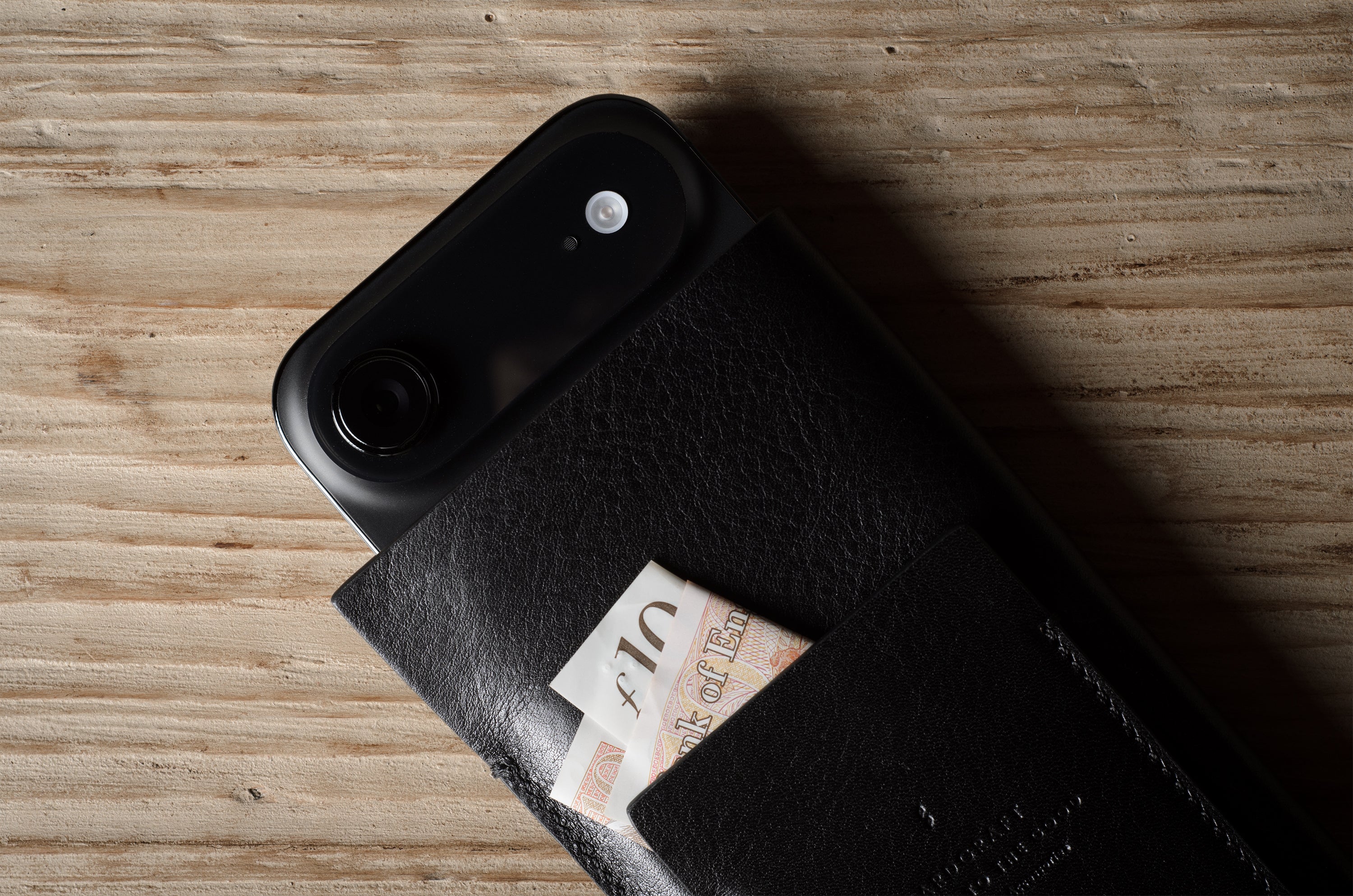 Black iphone case with a card on a wooden surface