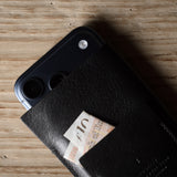 Black iphone case with a card holder attached to a smartphone on a wooden surface