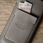 Gray leather iphone case with banknotes on a wooden surface