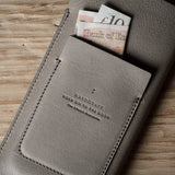 Gray leather iphone case with banknotes on a wooden surface