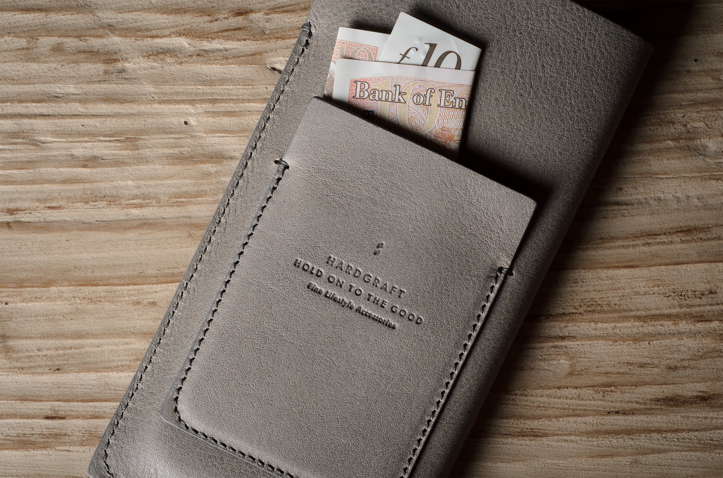 Gray leather iphone case with banknotes on a wooden surface