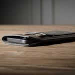 Grey leather iphone case on a wooden surface with a blurred background
