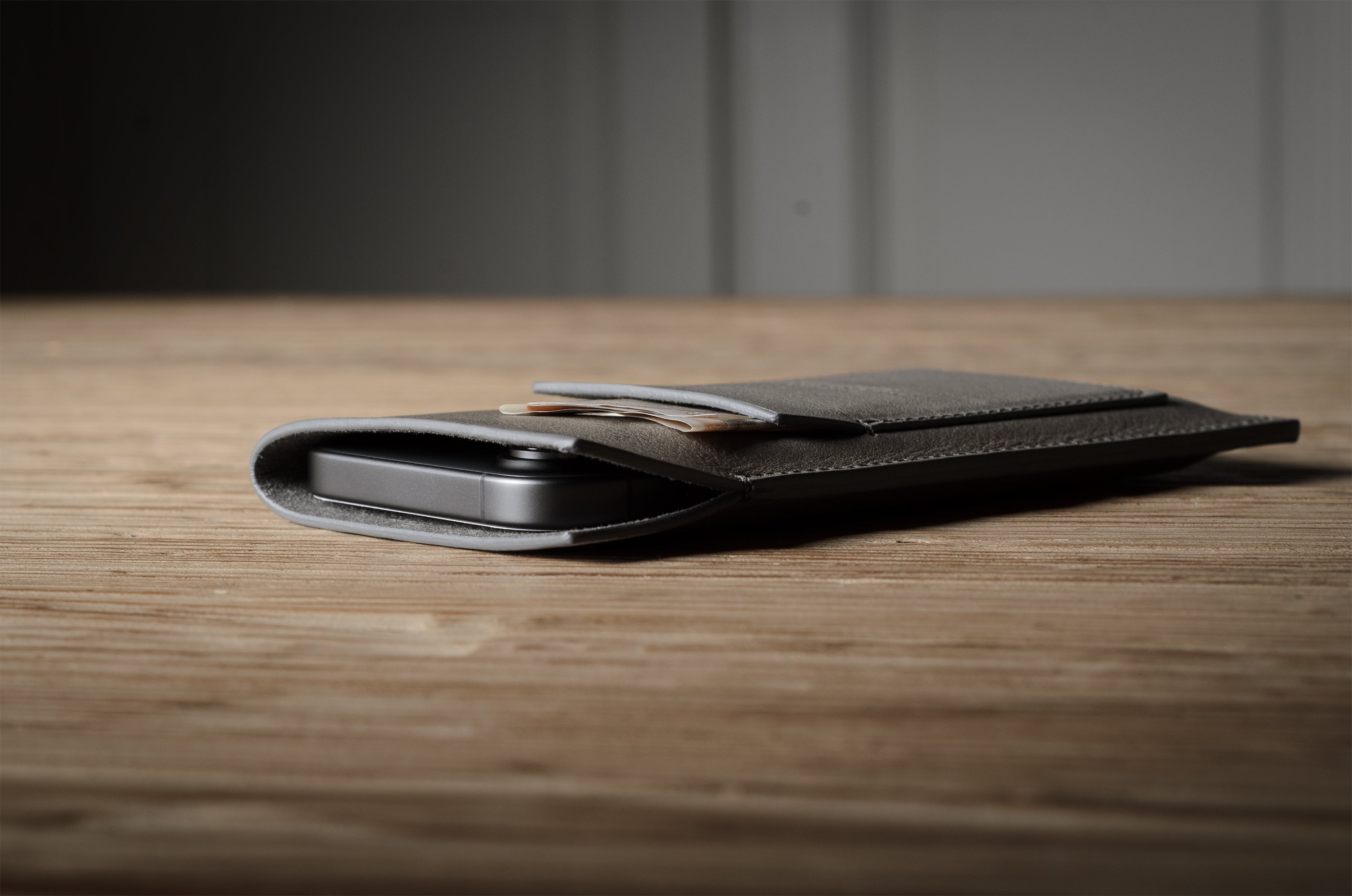 Grey leather iphone case on a wooden surface with a blurred background