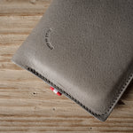 Gray leather iphone case with brand logo on a wooden surface