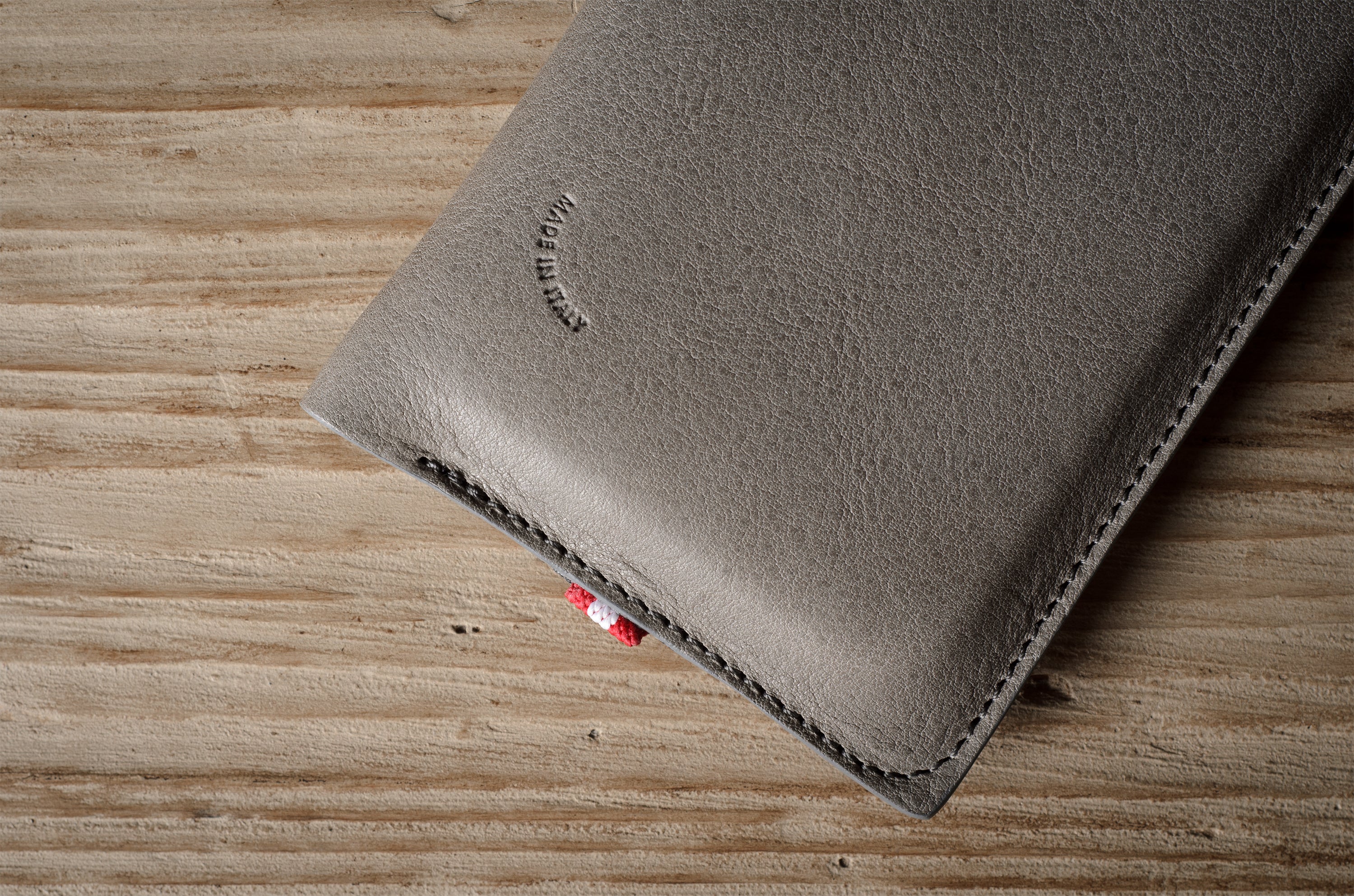 Gray leather iphone case with brand logo on a wooden surface