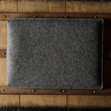 Gray wool felt laptop sleeve with brown leather on a wooden surface