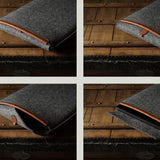 Gray wool felt laptop sleeve with brown leather on a wooden surface