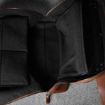 Brown leather bag with grey interior on a gray surface