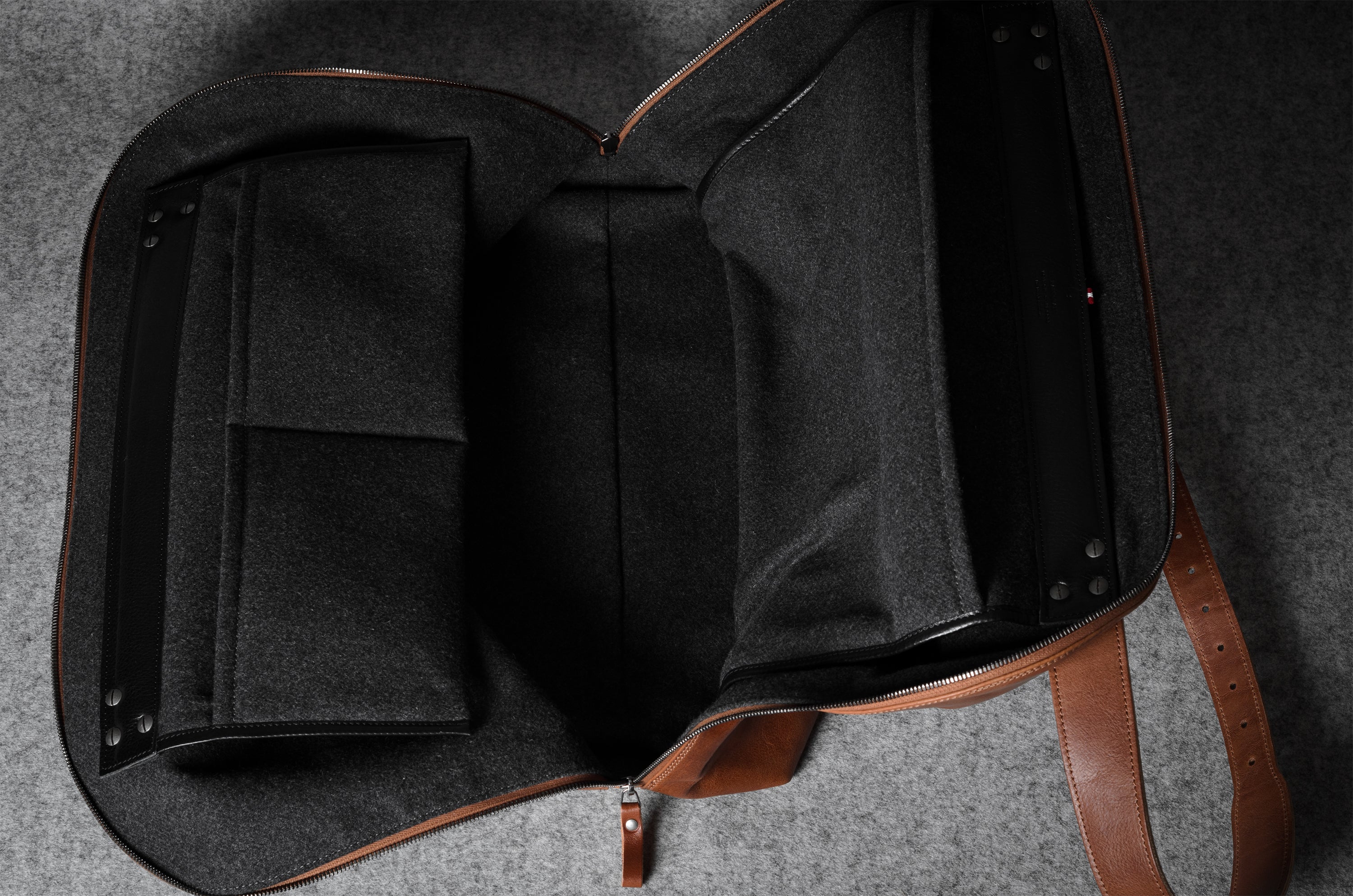 Brown leather bag with grey interior on a gray surface