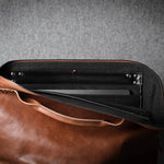 Brown leather laptop bag with a grey interior on a gray background