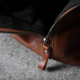 Close-up of a brown leather bag zipper on a dark fabric background