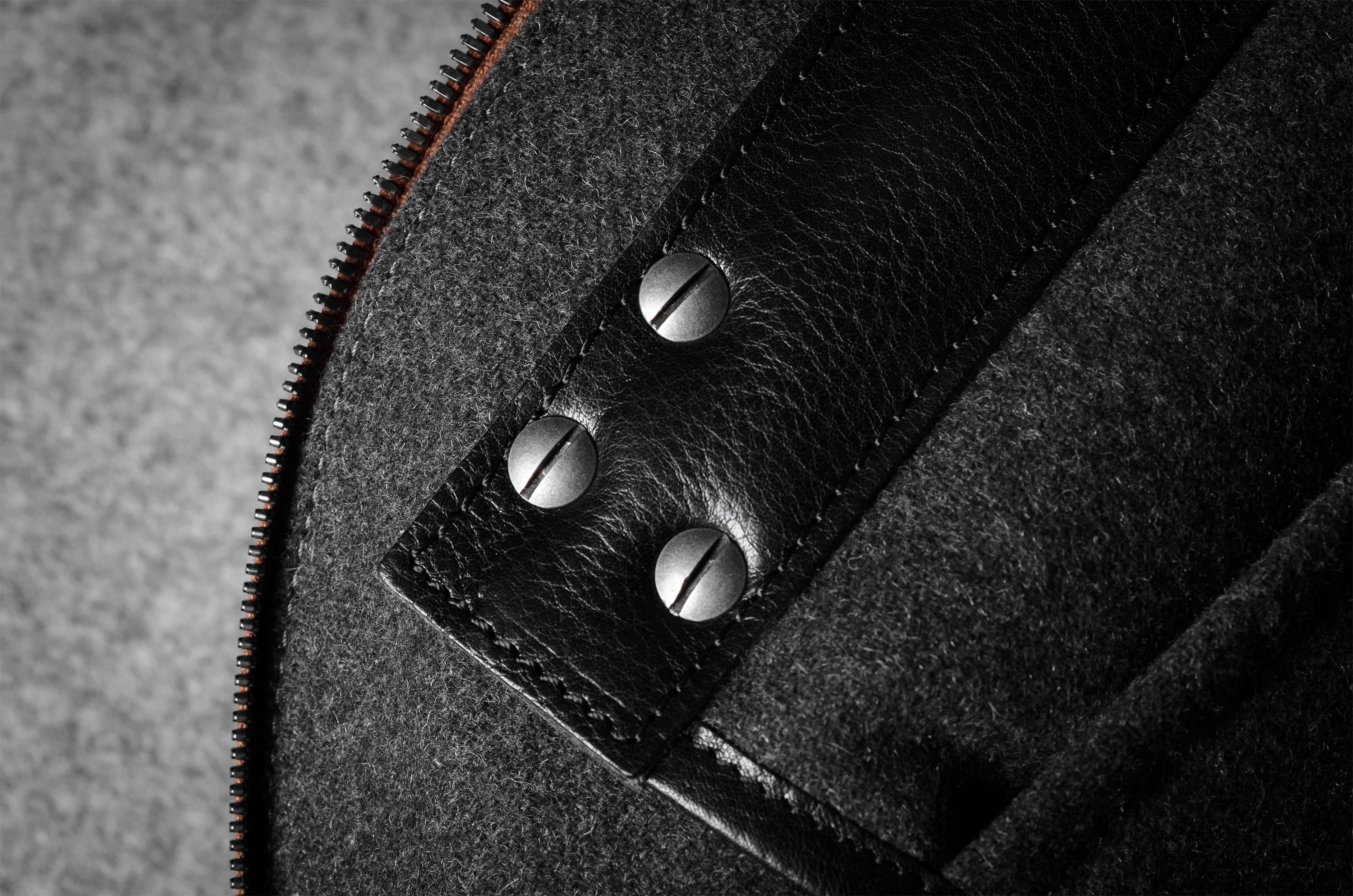 Close-up of a textured bag interior with a zipper and metal screws.