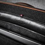 Close-up of a brown leather bag with a zipper and grey interior.