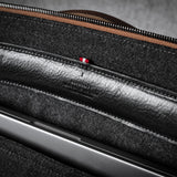 Close-up of a brown leather bag with a zipper and grey interior.