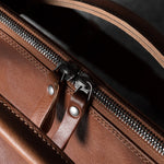 Close-up of a brown leather bag with a zipper
