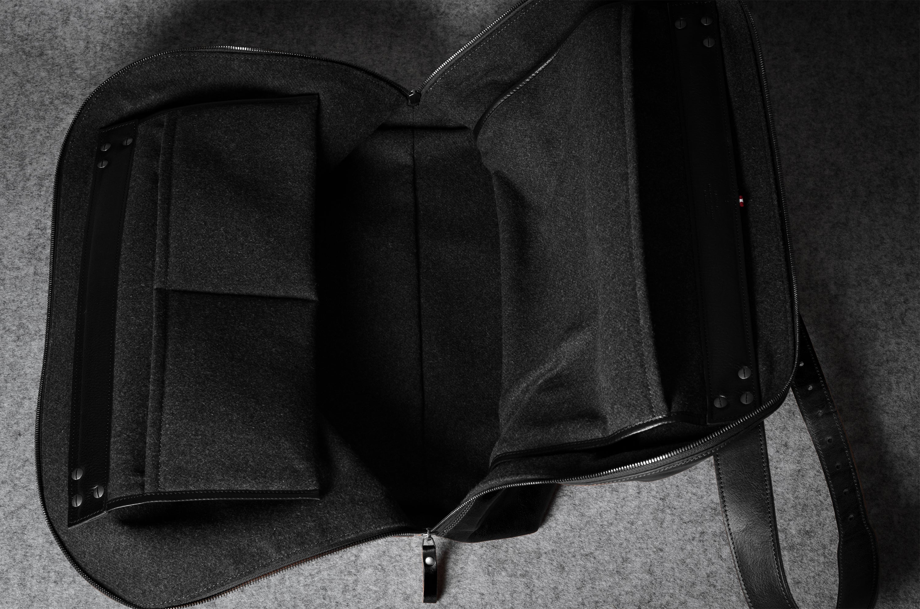 Black leather bag with a strap on a gray background