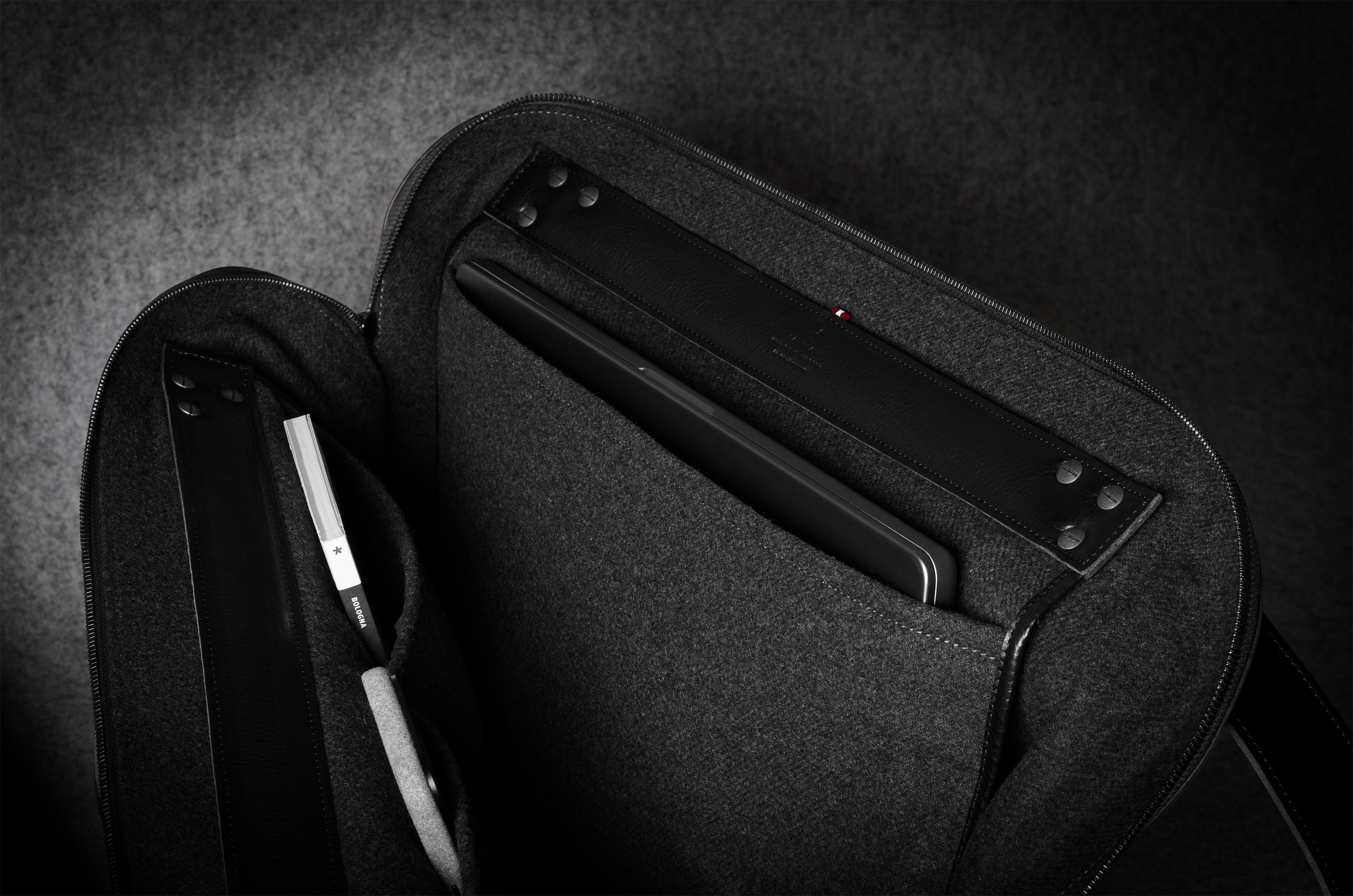 Black carrying case with a compartment for electronic devices on a dark background