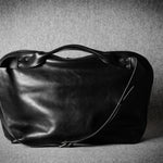 Black leather bag on a textured gray background