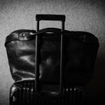 Black leather bag on metal suitcase with a handle on a textured gray background
