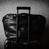 Black leather bag on metal suitcase with a handle on a textured gray background