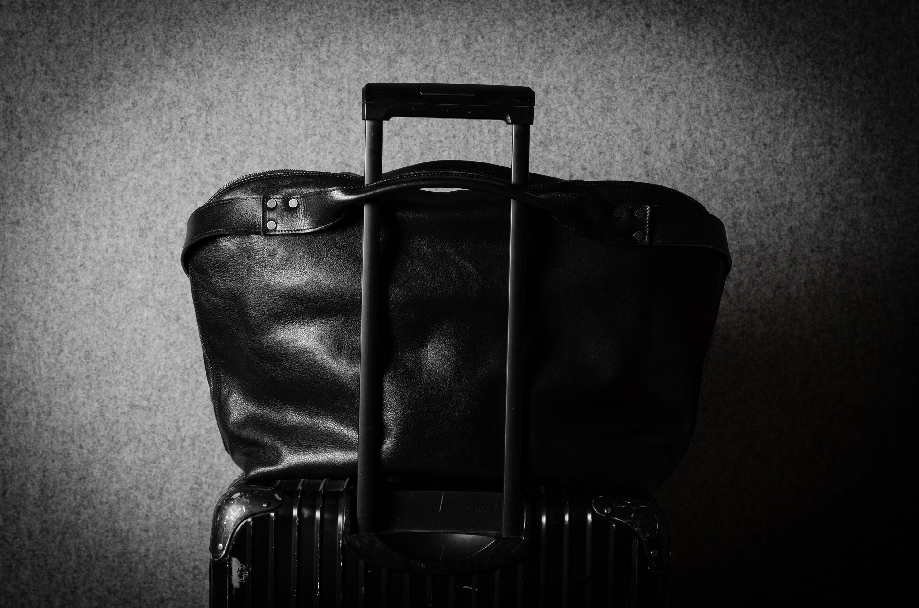 Black leather bag on metal suitcase with a handle on a textured gray background
