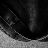 Close-up of a black leather bag with visible stitching on a textured surface