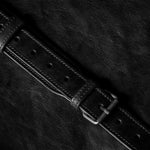 Close-up of a black leather belt on a dark textured surface