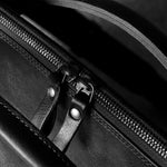 Close-up of a black leather bag with a zipper