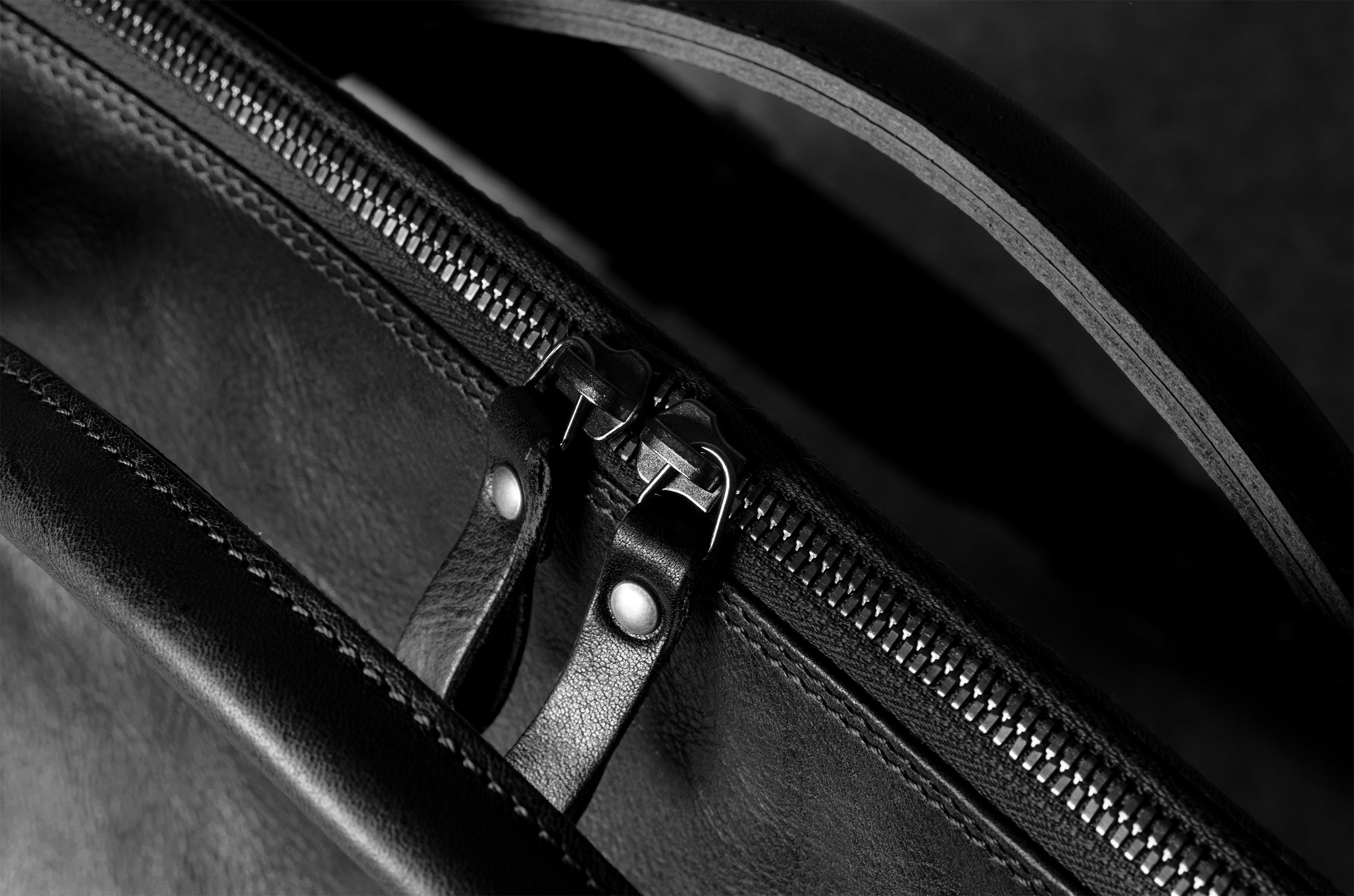 Close-up of a black leather bag with a zipper