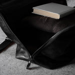 Black leather bag with a book on a gray surface