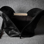 Black leather bag with a book inside on a gray background