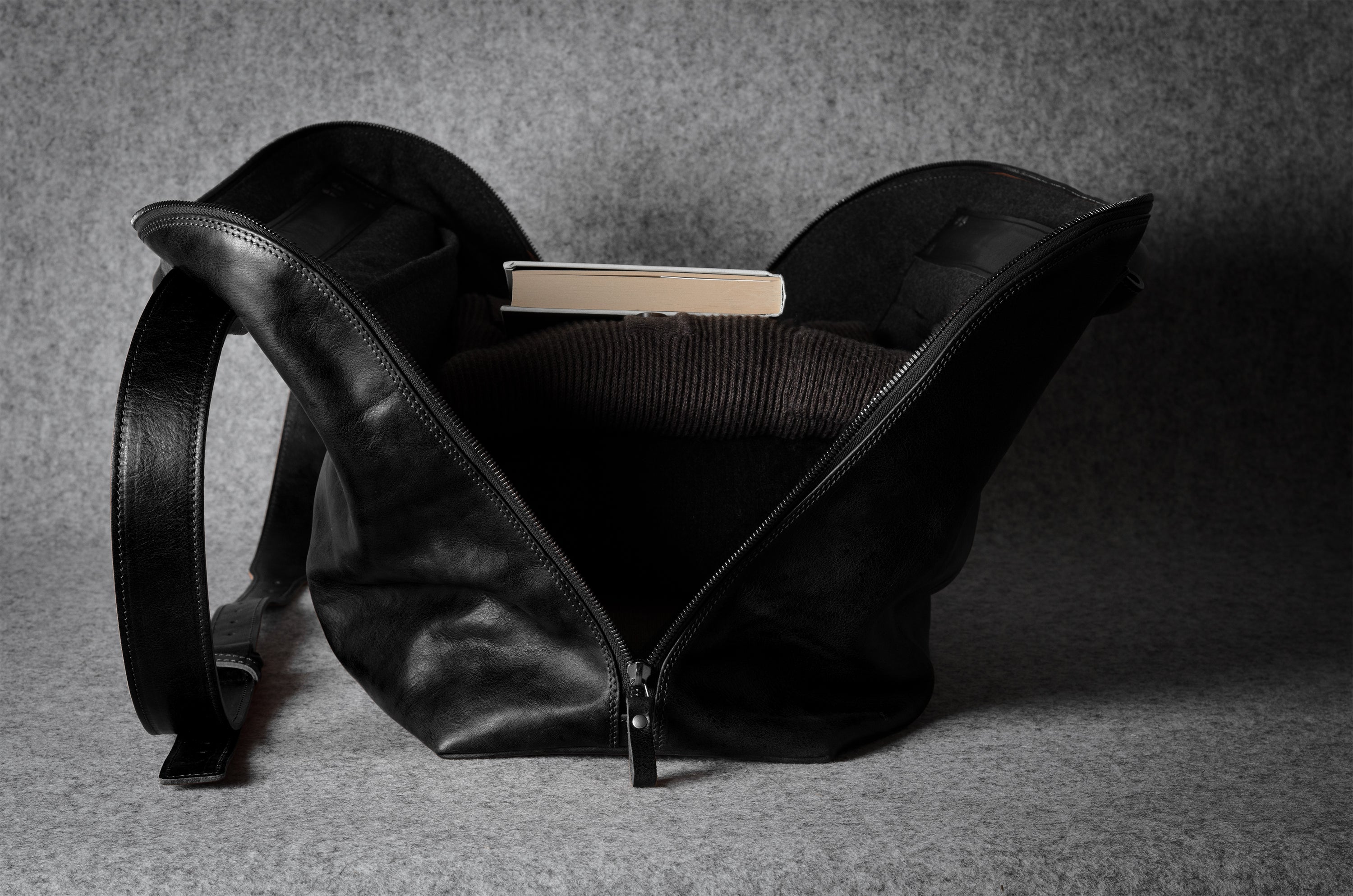 Black leather bag with a book inside on a gray background