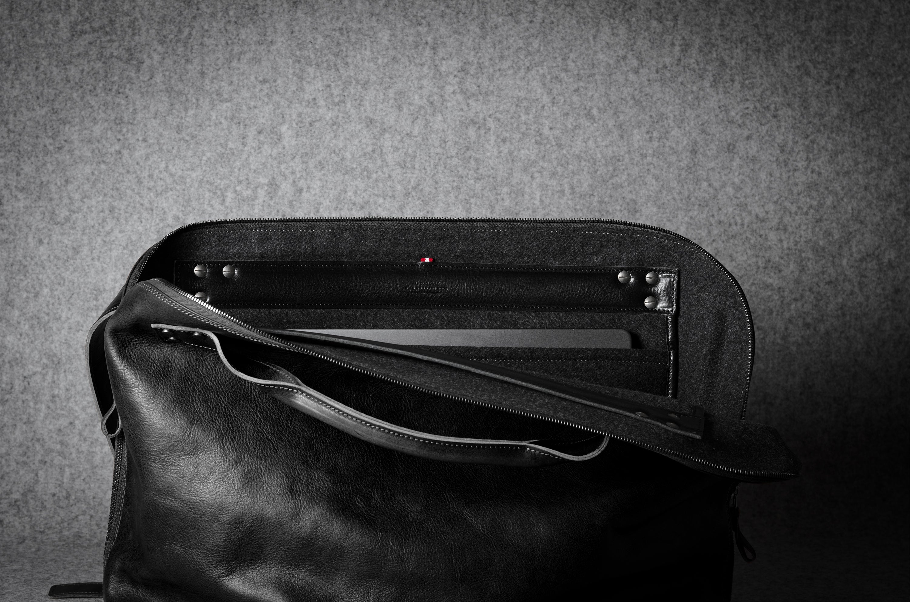 Black leather bag with a textured gray background