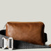 Brown leather bag with a gray strap on a light beige background