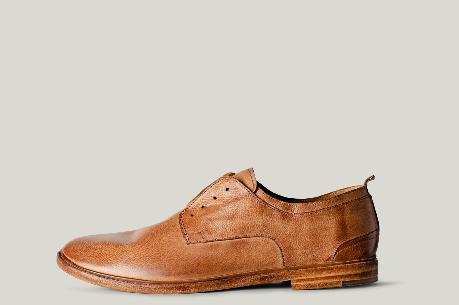Brown leather dress shoe on a light gray background
