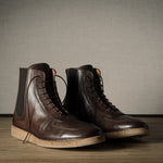 Pair of brown leather boots on a wooden surface with a neutral background