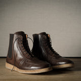 Pair of brown leather boots on a wooden surface with a neutral background