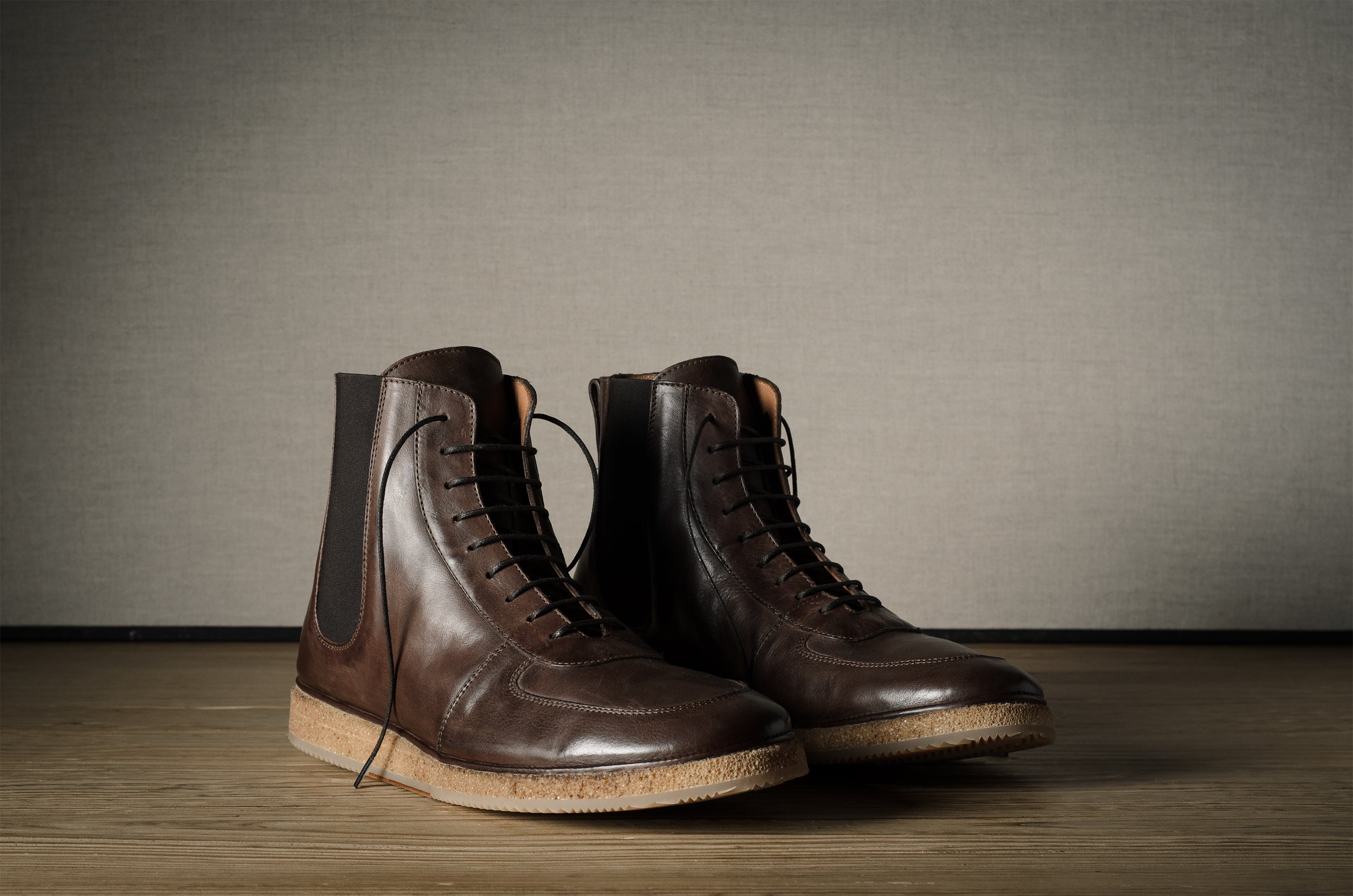 Pair of brown leather boots on a wooden surface with a neutral background