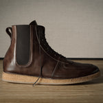 Brown leather boot with cork sole on a wooden floor