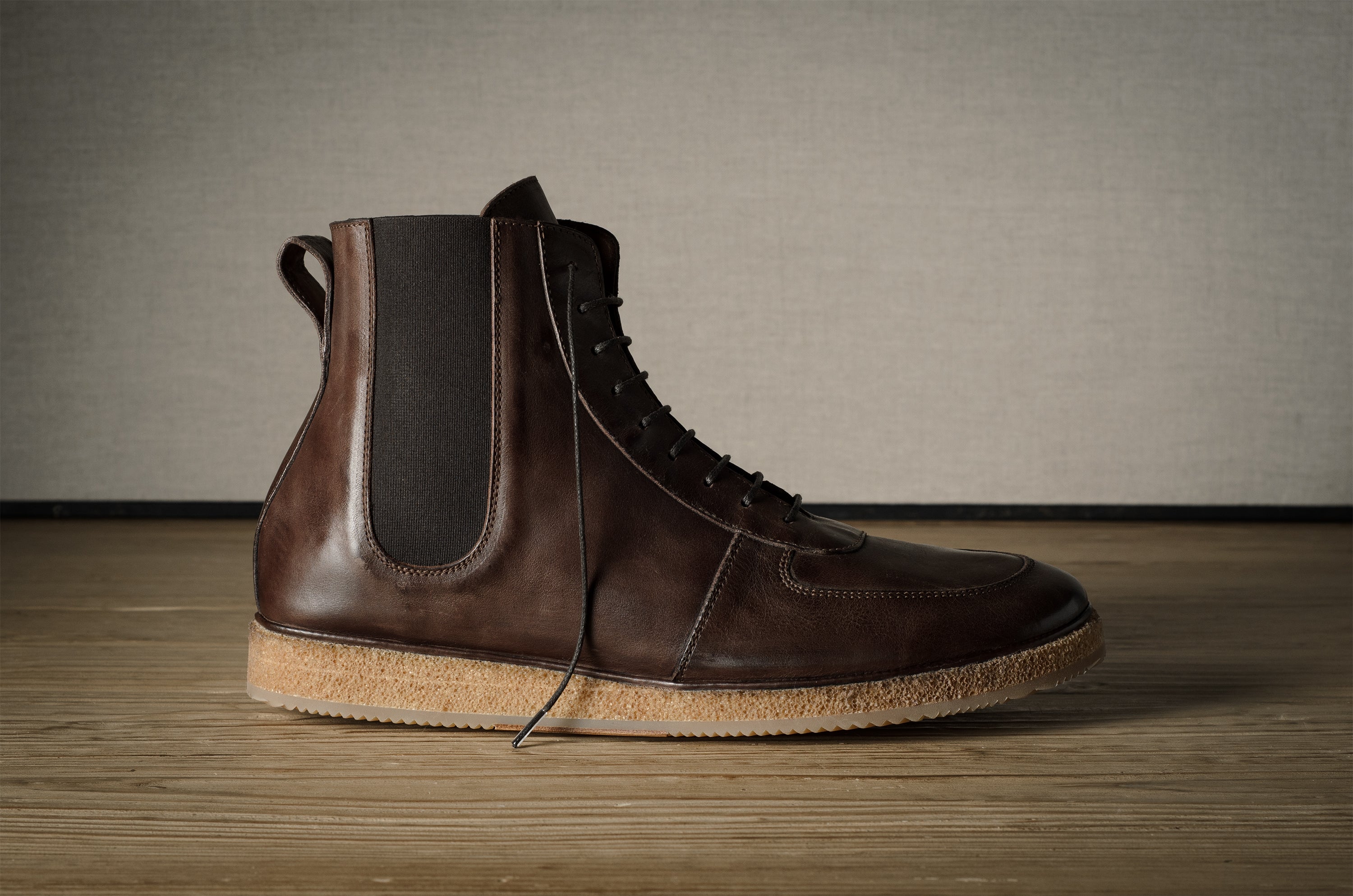 Brown leather boot with cork sole on a wooden floor