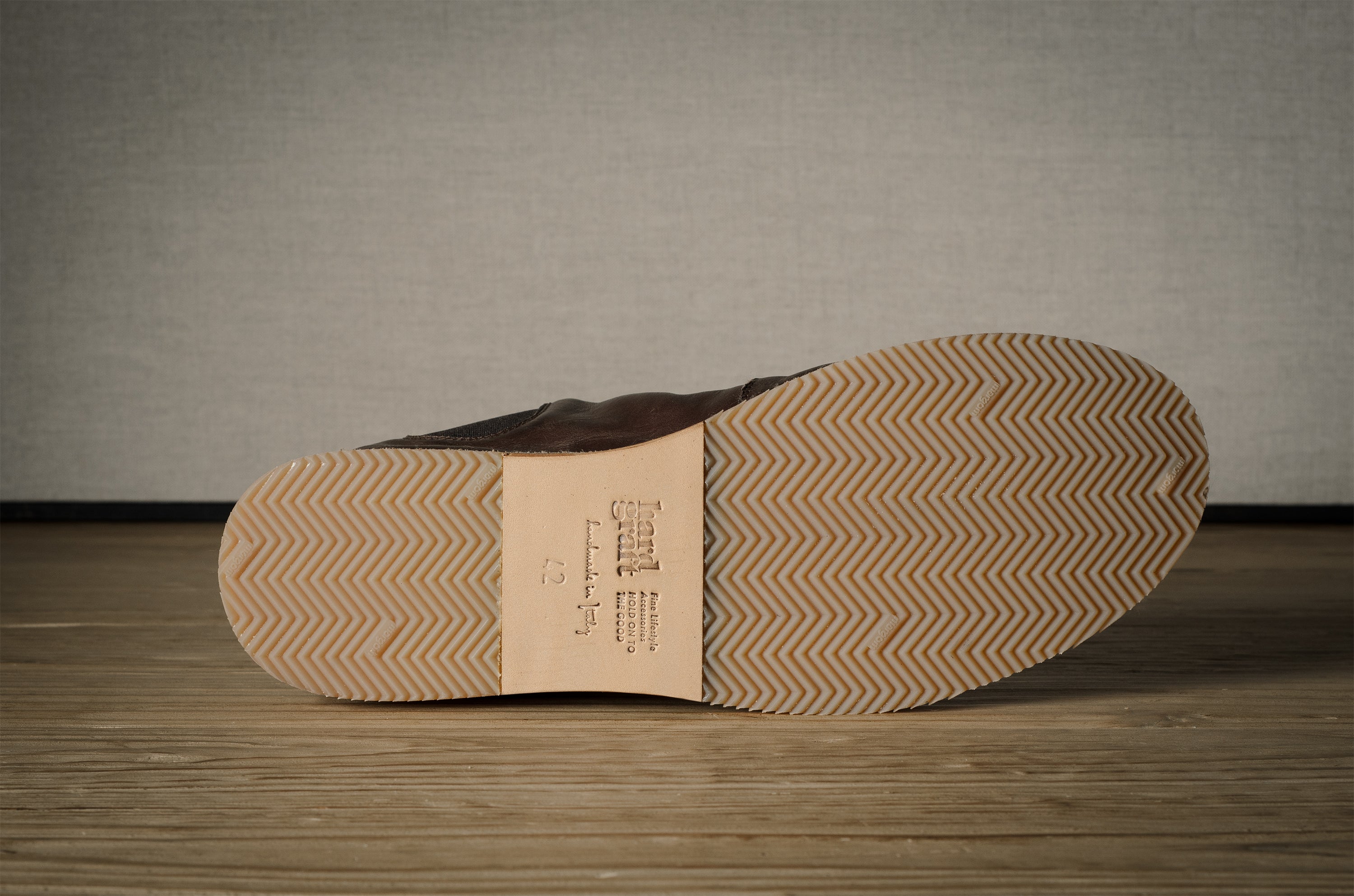 Close-up of a shoe sole with tread pattern on a wooden floor.