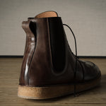 Brown leather boot on a wooden floor with a neutral background