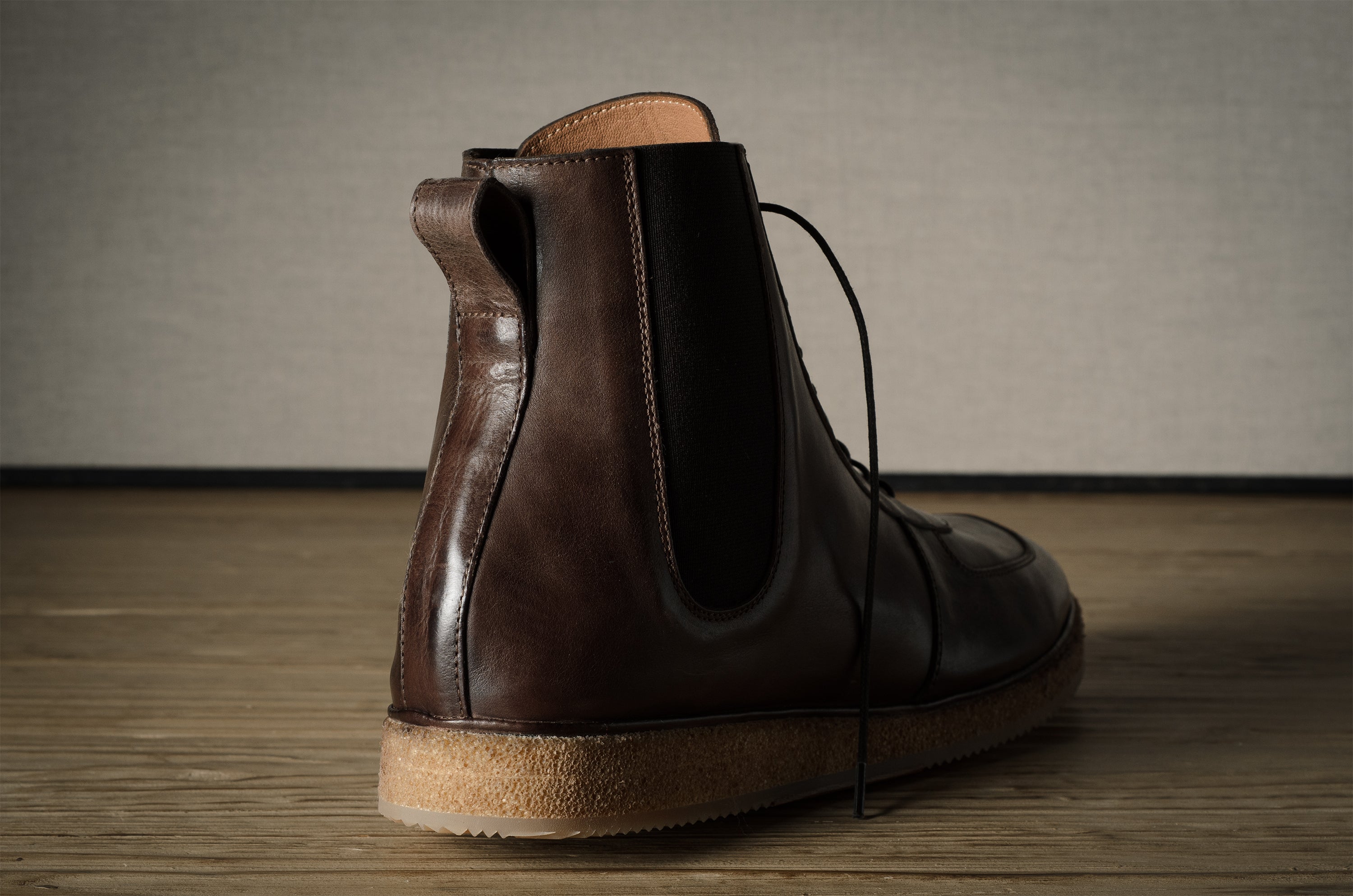 Brown leather boot on a wooden floor with a neutral background