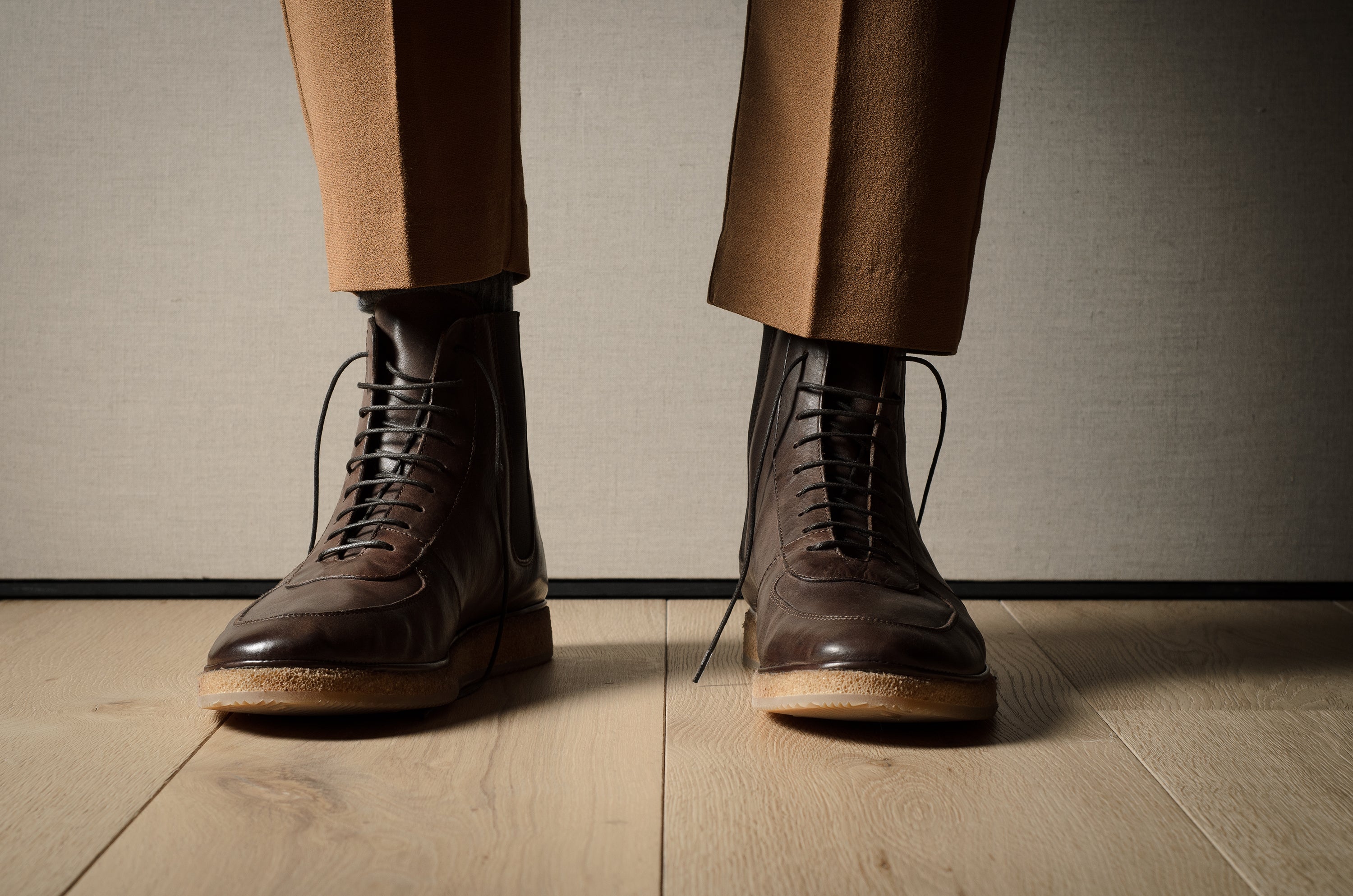Brown leather boots and pants on a wooden floor with a neutral background